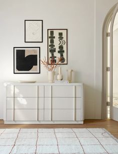 a living room with white furniture and pictures on the wall above it's dresser