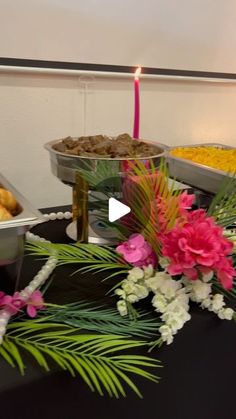 a table topped with plates and bowls filled with food next to a pink flower arrangement