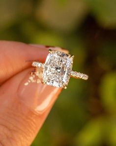 a close up of a person's hand holding an engagement ring