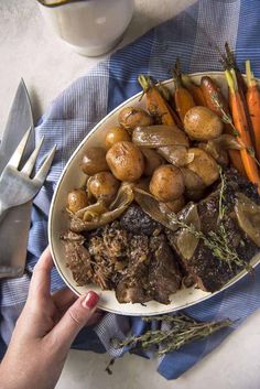 a plate full of roast, potatoes and carrots on a blue napkin with a fork