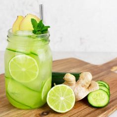 a mason jar filled with cucumber, lemon and lime slices on a cutting board