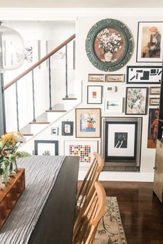 a dining room table with chairs and pictures on the wall