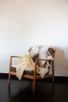 a chair with a blanket on it in front of a white wall and black floor