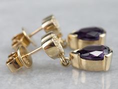 Deeply hued amethyst gemstones have been set into polished mountings of yellow gold. The open back allows light through the entire stone, bringing plenty of glitter into these pretty stones. We've finished these vibrant, pretty earrings with secure post-back findings, decorated with sparkling polished gold diamond hearts.Metal: 14K Yellow Gold Gem: 2 Amethyst totaling 2.00 Carats Gem Measurements: 8.6 x 6 mm, Pear Cut Accents: 12 Diamonds totaling .30 Carats, G in Color, SI1 in ClarityEarrings Length: 21 mm Earrings Width: 7 mmMarks: “14K” Stamped on the Reverse Pocket Watch Chain, Watch Chain, Diamond Drops, Pretty Earrings, Diamond Drop Earrings, Amethyst Gemstone, Pear Cut, Pearl Pendant, Charm Earrings