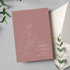 the wedding card is next to an envelope with flowers on it, and greenery