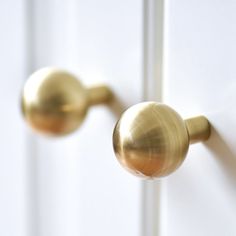 two brass door knobs on the side of a white door, one with a round handle