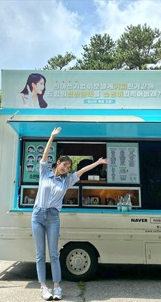 a woman standing in front of a food truck with her hand up to the sky