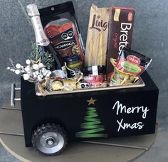 a christmas gift box with food and snacks in it sitting on a small table next to a wall