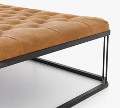 a brown leather bench sitting on top of a metal frame stand with black legs and feet