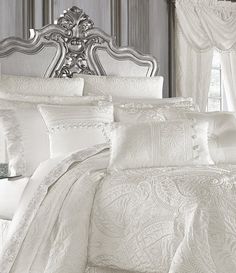 a bed with white comforters and pillows in a bedroom next to a window at night