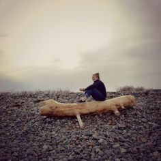 a man sitting on top of a wooden log