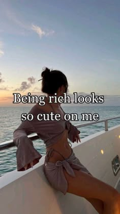 a woman is sitting on the edge of a boat looking out at the ocean and saying being rich looks so cute on me