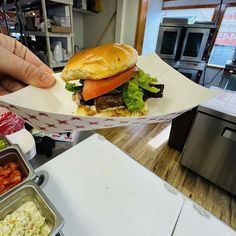 a person holding up a sandwich in a paper container