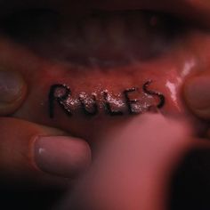 the word rules written in black ink on someone's mouth with their tongue out