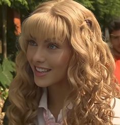 a woman with long blonde hair wearing a white shirt and pink flowered headband