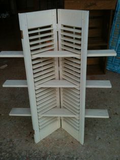 a white wooden shelf with shutters on the top and bottom shelves in front of it