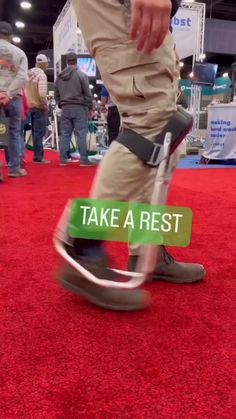 a man walking across a red carpet covered floor next to a sign that says take a rest