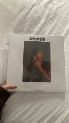 a person holding up a white album on a bed