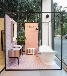 a bathtub and sink in a room with large glass windows that look out onto the street