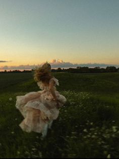 a woman in a dress running through a field