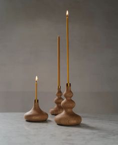 two candles sitting on top of a table next to each other with one candle in the middle