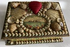 a decorative box with seashells and shells on it's sides, along with a red heart