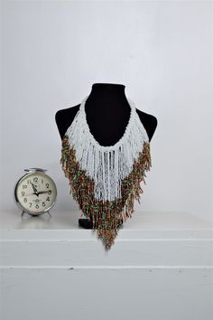 Unique African Maasai Handcrafted Beaded Necklace with an Elegant Look and Brilliant Finish. Circumference = 16 Inches/ 41 Centimeters. Color =White and Multi-Color Maasai Beads. Fringe = 10 Inches / 26 Centimeters. **GET FREE SHIPPING FOR ADDITIONAL ITEMS PURCHASED. Yes, Buy Multiple Items and pay shipping for 1 item only- The rest ships Free. (No Limits on the number of Multiple items). With a faster delivery time of 3 days via DHLExpress, Worldwide. Ordinary/Standard Shipping also available u Traditional Beaded Chain Jewelry For Beach, White Bohemian Choker With Colorful Beads, Bohemian Bib Necklaces With Colorful Round Beads, White Bohemian Jewelry With Large Beads, White Faceted Beads Jewelry For Festival, White Jewelry With Faceted Beads For Festival, Bohemian Bib Necklace With Round Beaded Chain, Beaded Bohemian Choker, Bohemian Bib Necklace With Beaded Chain