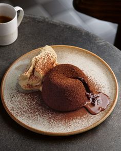 two desserts sit on a plate next to a cup of coffee