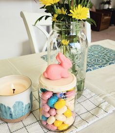 a glass jar filled with candy sitting on top of a table next to a candle