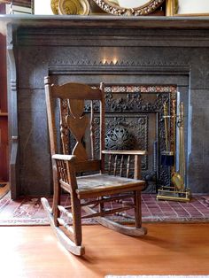 a rocking chair sitting in front of a fire place with a mirror on the wall