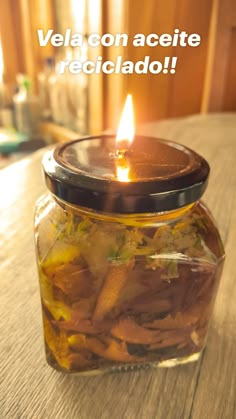 a jar filled with food sitting on top of a wooden table next to a candle