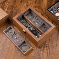 three wooden boxes with jewelry inside on a wood floor next to two watches and bracelets