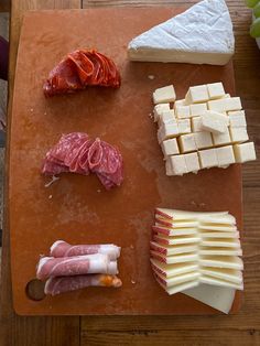 several different types of cheese and meats on a cutting board