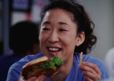 a woman is smiling while eating a sandwich