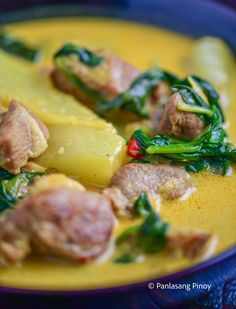 a blue bowl filled with meat and vegetables on top of a yellow table cloth,