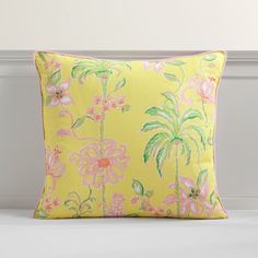 a yellow pillow with pink flowers and palm trees on it