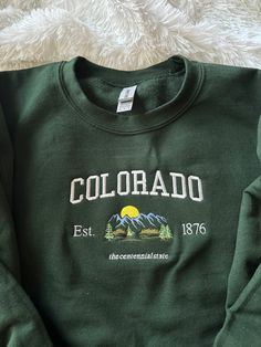 Colorado, stand up! Comfy sweatshirt with Colorado in a varsity-like font featuring a mountain design. This pullover Crewneck will keep you stylish and warm with its fleece lined fit.  You can add names on the sleeve for $5 extra!  This sweatshirt is available in 6 colors:  ✨ Military Green ✨ Forest Green ✨ Sand ✨ White (words will be in black) ✨ Light Blue ✨ Navy ✨ Heather Gray If there is a color you have in mind other than the ones available, send me a message and I can help! -Sweatshirt bran Colorado Cool Gifts, Cheap Women's Sweatshirt For College, Cheap College Sweatshirt With Sublimation Print, Trendy Cheap College Sweatshirt, Cheap Fleece Sweatshirt With Embroidered Graphics, Cheap Crew Neck Sweatshirt For Adventure, Cheap Fall Sweatshirt For College Events, Cheap Green Outdoor Sweatshirt, Cheap Cozy College Sweatshirt