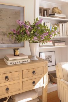 a vase with flowers sitting on top of a wooden table next to a white chair