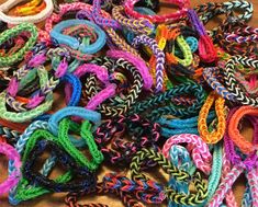 many different colored bracelets are on the table together and one has a knot at the end