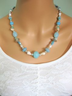 Natural stone beaded necklace with blue stone beads. This is a one of a kind necklace the only one made. Click to see it. This beautiful beach style necklace is made with light sea foam blue beads, shells, shell pieces, freshwater pearls, and silver metal beads. This necklace is one of a kind, and makes a great gift for women. The necklace has a lobster clasp, and is a short necklace at 22 inches long, but can be made shorter, or longer with a chain extension, on request. This necklace is ready Blue Strand Shell Necklace In Beachy Style, Turquoise Shell Beaded Necklaces With Round Beads, Turquoise Shell Beaded Necklaces, Blue Beaded Shell Strand Necklace, Blue Beaded Shell Necklace In Beachy Style, Bohemian Blue Shell Beaded Necklaces, Light Blue Round Bead Necklaces For The Beach, Blue Beaded Beachy Shell Necklace, Blue Bohemian Shell Beaded Necklaces