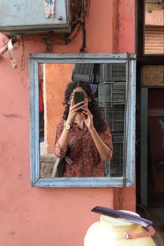 a woman taking a selfie in front of a mirror with her cell phone up to her ear