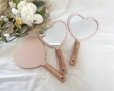 two heart shaped mirrors sitting on top of a bed next to a bouquet of flowers