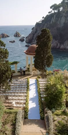 an outdoor ceremony setup with chairs and trees by the water in front of a gazebo