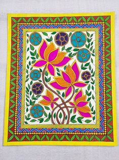 an embroidered square with colorful flowers and leaves on the side, sitting on a white surface