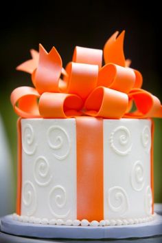 an orange and white bow on top of a cake with swirls in the icing