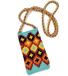 a cell phone is laying next to a crocheted bag with a lanyard