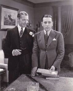 two men standing next to each other near a table with a box on top of it