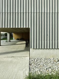 an open garage door on the side of a building with gravel and grass around it