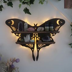 a butterfly shaped wall mounted shelf with candles and rocks on it's back side