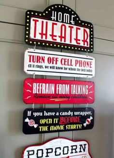 some signs are hanging on the wall in front of a door that says, home theater turn off cell phone if you have a candy bar open it before the movie starts